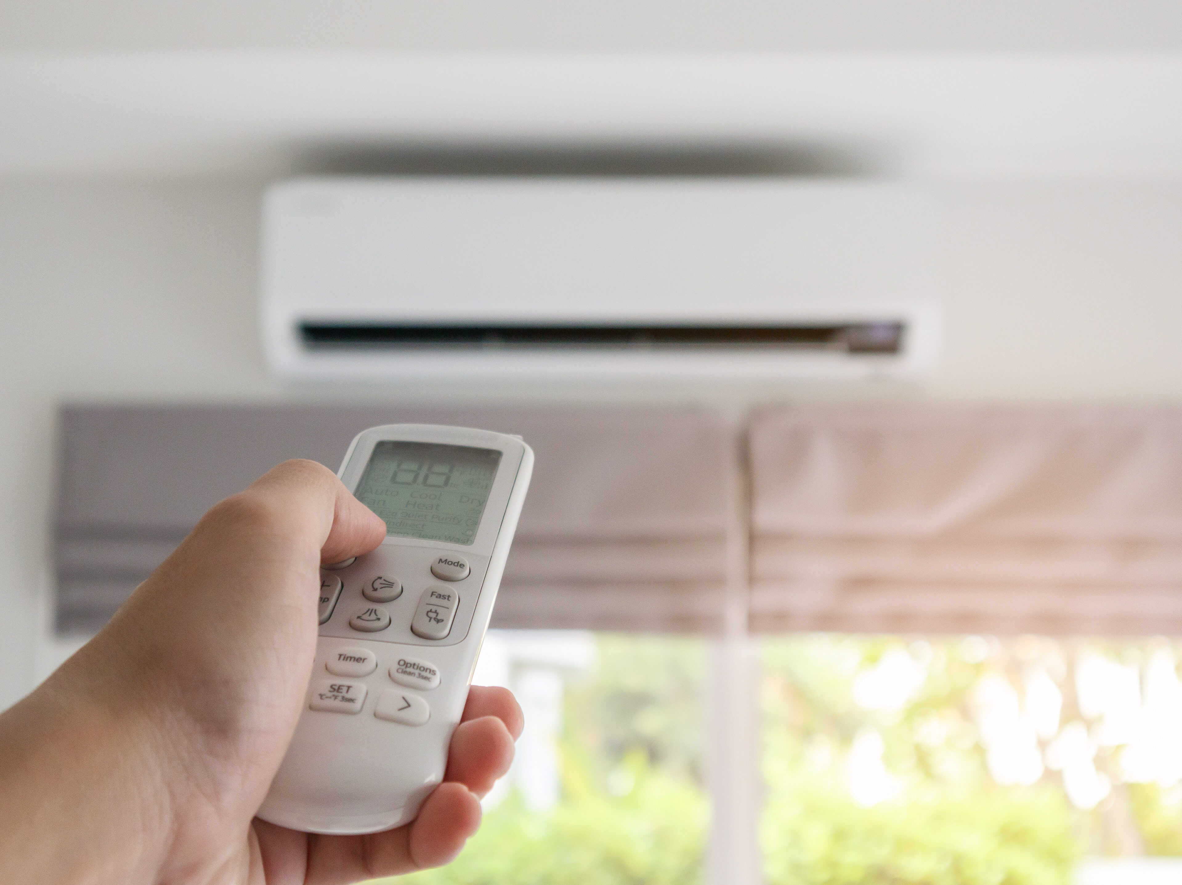 Hand with remote control directed on air conditioner